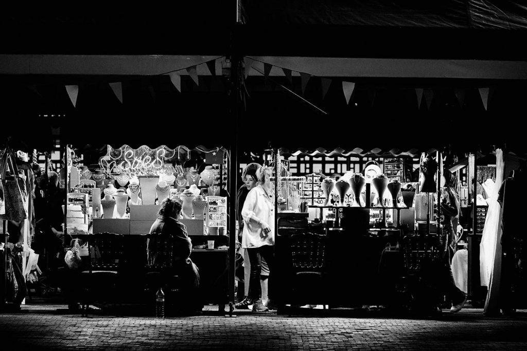 Black and white photo of a vibrant night market jewelry stall showcasing necklaces and accessories.