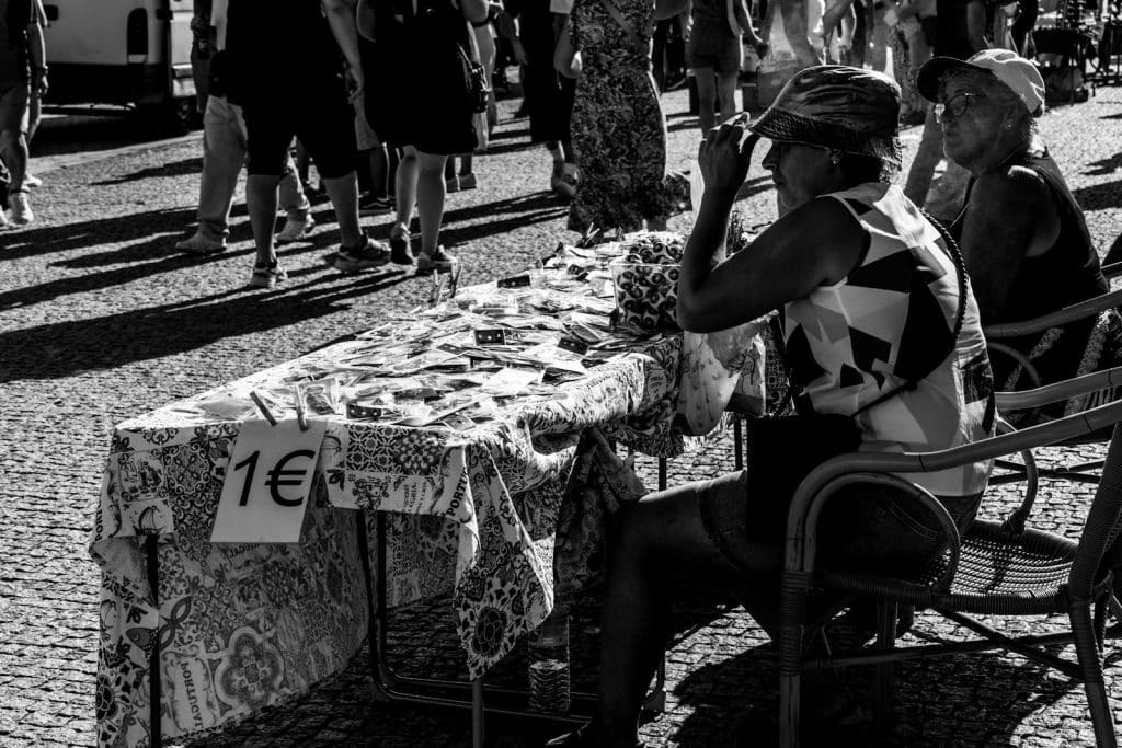 Black and white photo of people at a street market in Porto, Portugal, selling goods.