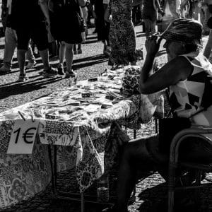 Black and white photo of people at a street market in Porto, Portugal, selling goods.